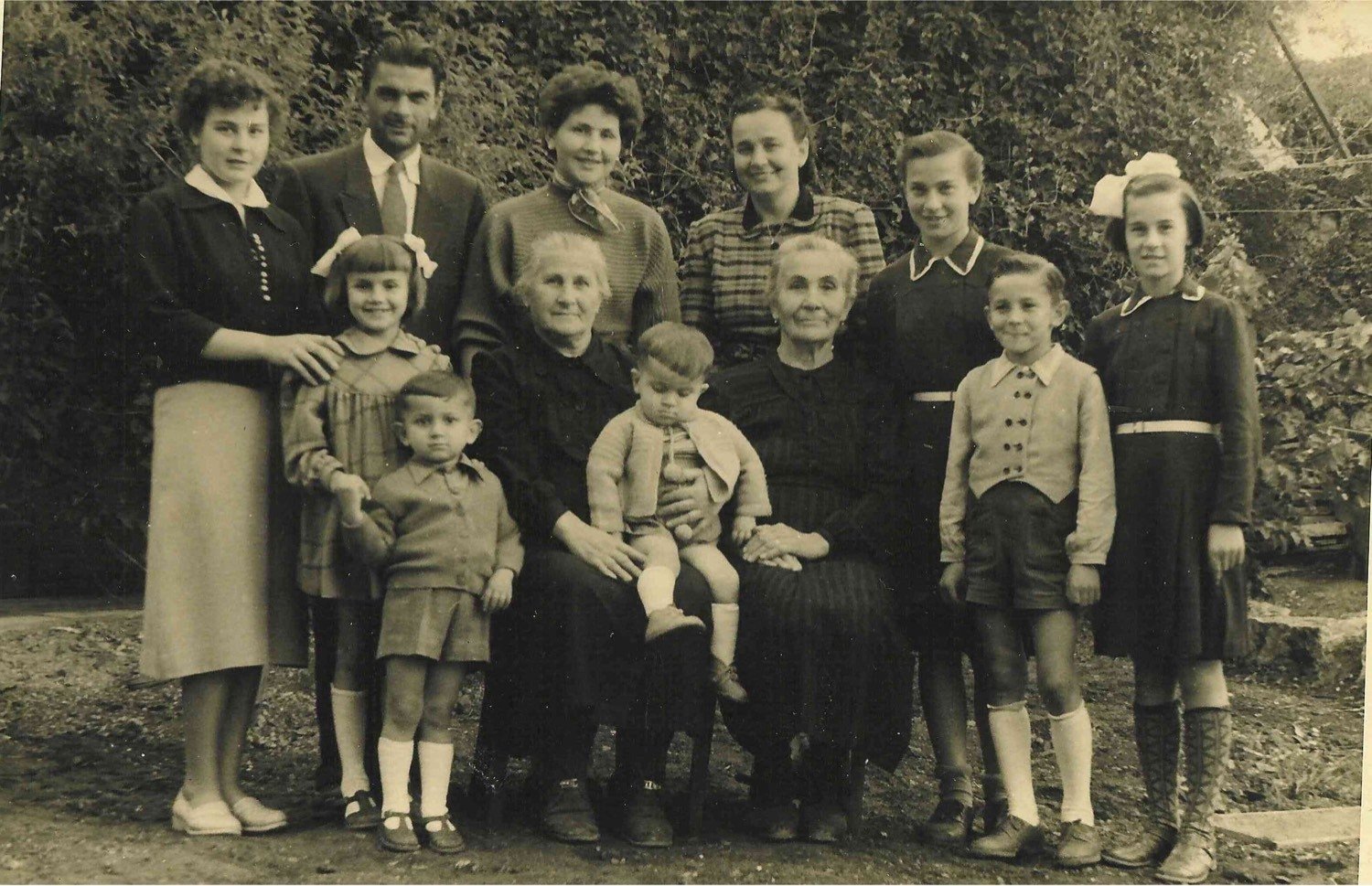 Multi-generational family group in a garden, 1950s