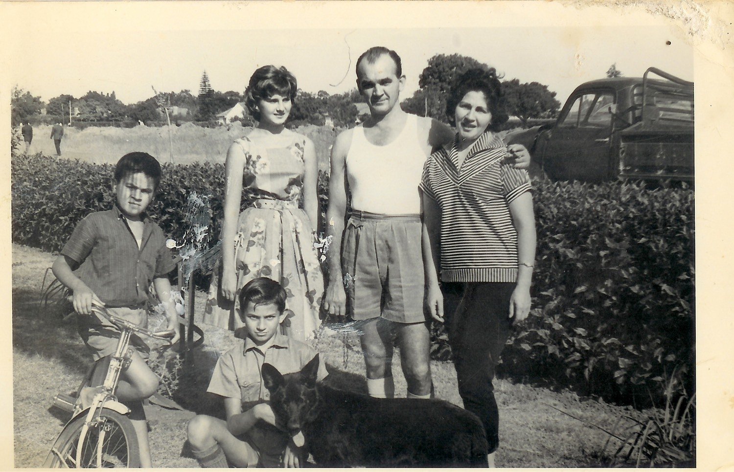 Five people and a dog outdoors beside a truck, late 1950s