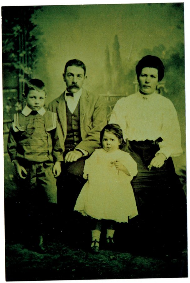 Studio portrait of a man, a woman, a boy of about seven and a small girl in a white dress.